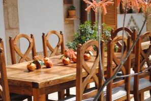 Uma mesa de jantar de madeira com cadeiras, plantas em vasos e objetos decorativos.