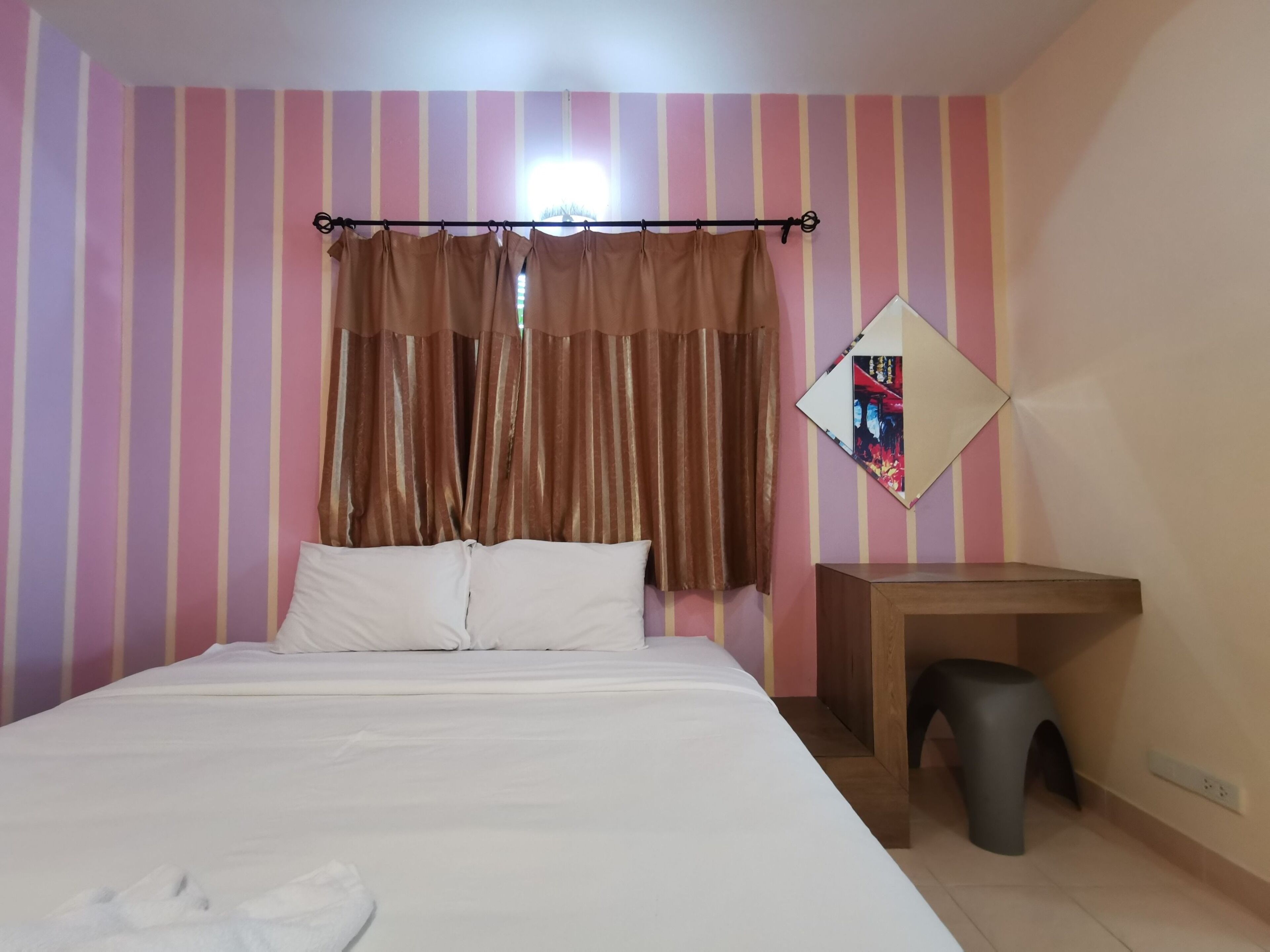 A hotel room with a bed, a desk, a chair, and a mirror on the wall.