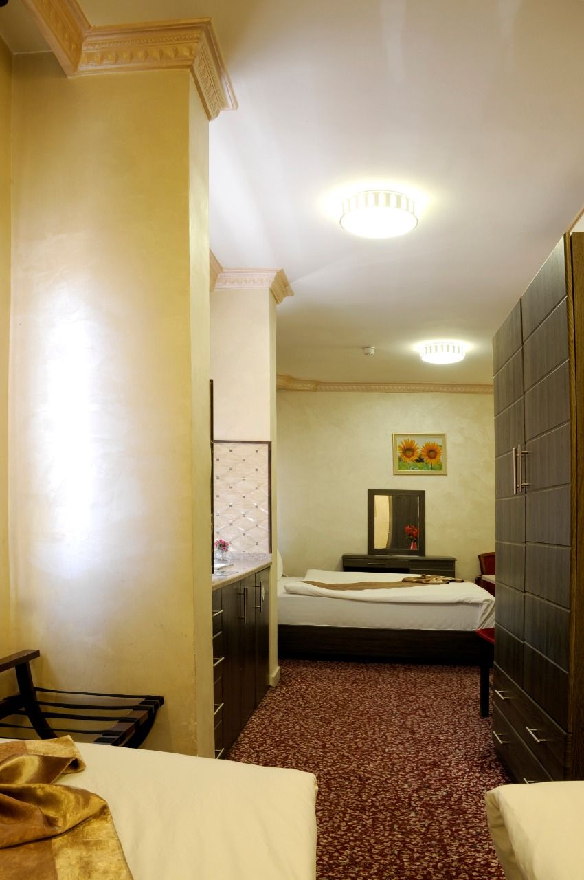 A hotel room with a bed, a dresser, a mirror, and a small table.