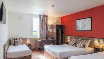 Une chambre d’hôtel avec deux lits, un bureau, une chaise, une armoire et un mur d’accent de couleur rouge.