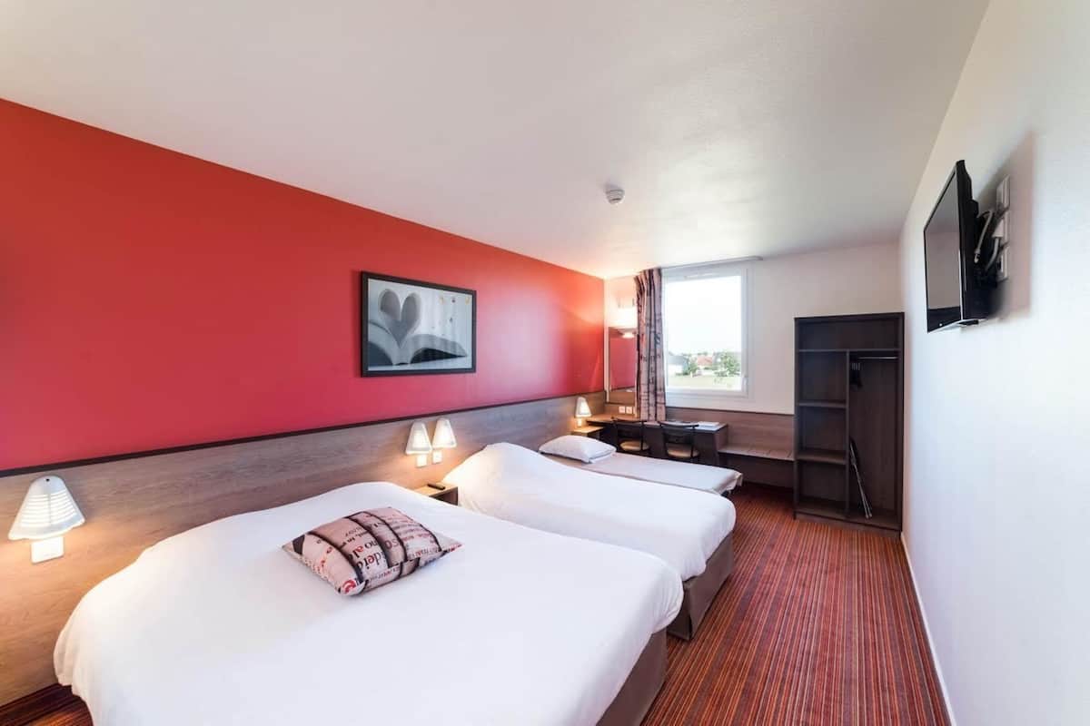 Hotelkamer met twee bedden, een bureau, een stoel, een televisie en een raam met uitzicht.