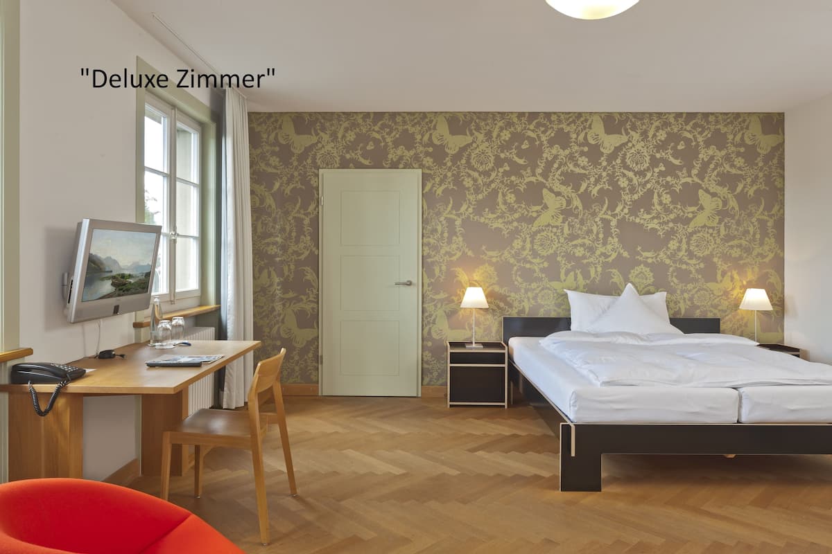 Une chambre d’hôtel équipée d’un lit, d’un bureau, d’une chaise et d’un téléviseur fixé au mur.