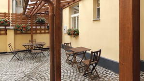 A courtyard with a wooden pergola, a table with chairs, and potted plants. - Anyday Apartments (Prague)