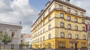 A multi-story yellow building with a stone facade, multiple windows, and a visible entrance. - Anyday Apartments (Prague)