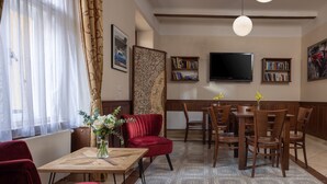 A living room with a dining area, red chairs, a wooden table, a TV, and bookshelves. - Anyday Apartments (Prague)