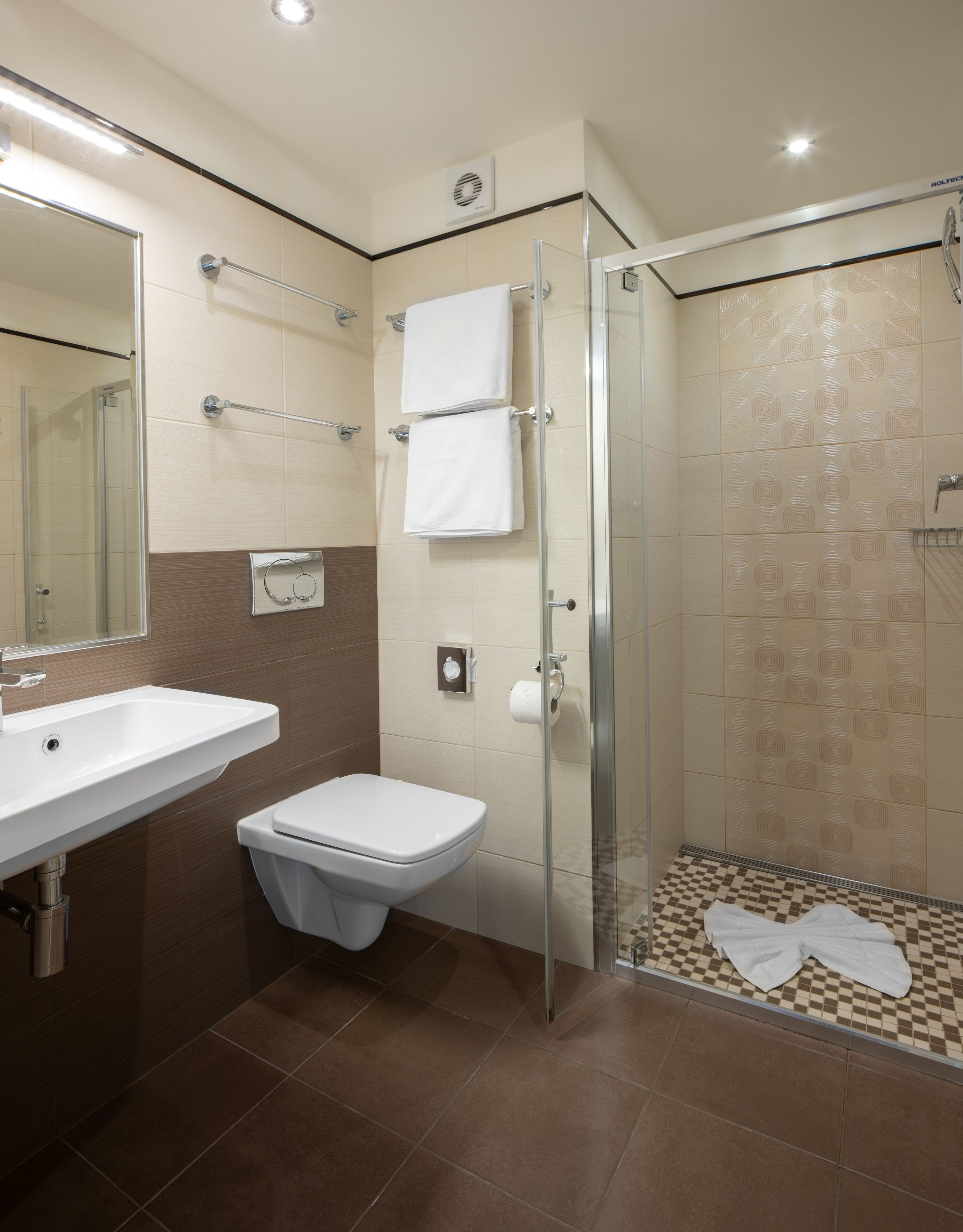 A modern bathroom with a glass-enclosed shower, a white sink, and a toilet.