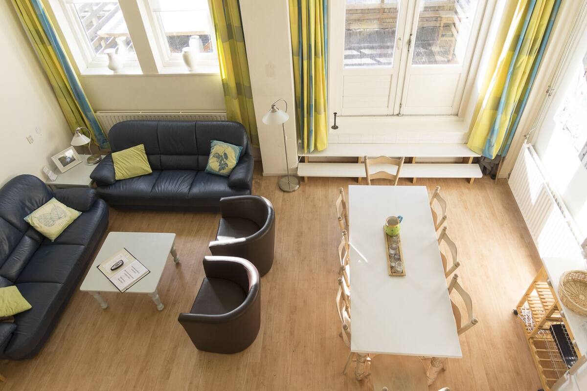 A living room with a sofa, two armchairs, a coffee table, and a dining table.