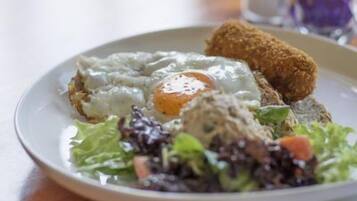 Een bord met een gebakken ei, een stukje paneermeelkip en een salade.