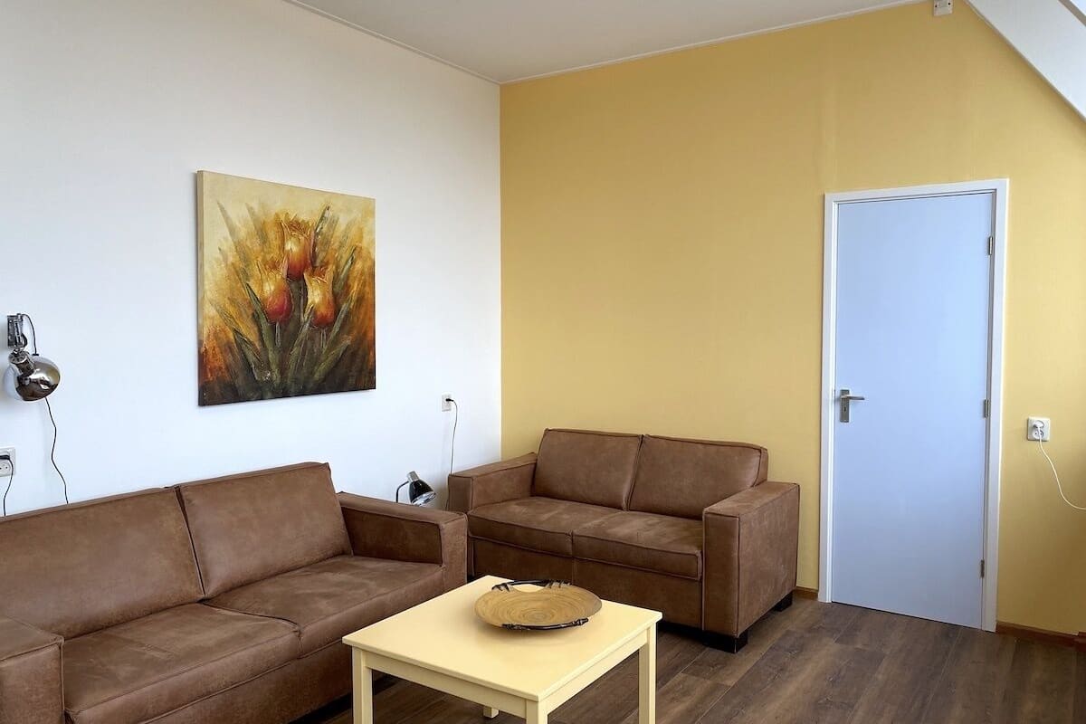 A living room with two brown sofas, a small table, and a door.