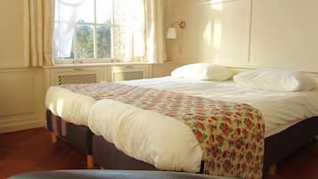 Un dormitorio con cama, ventana con cortinas, lámpara de pared y radiador.