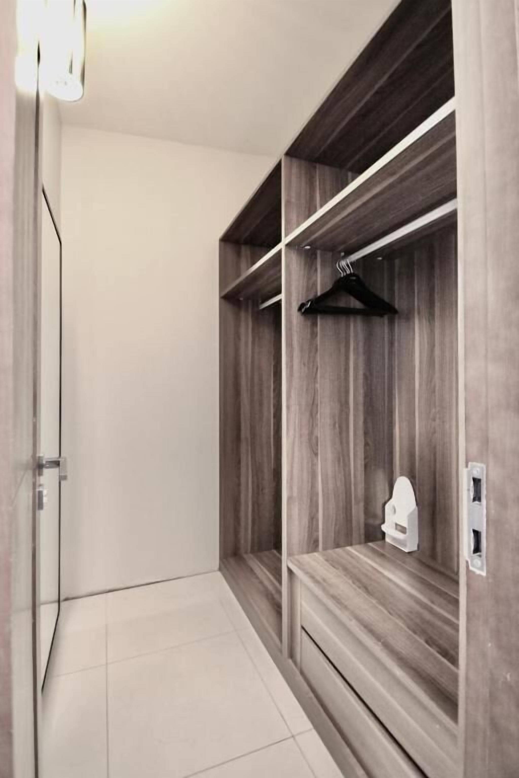 A hallway with a wooden wardrobe, a hanging rack, and a light switch.