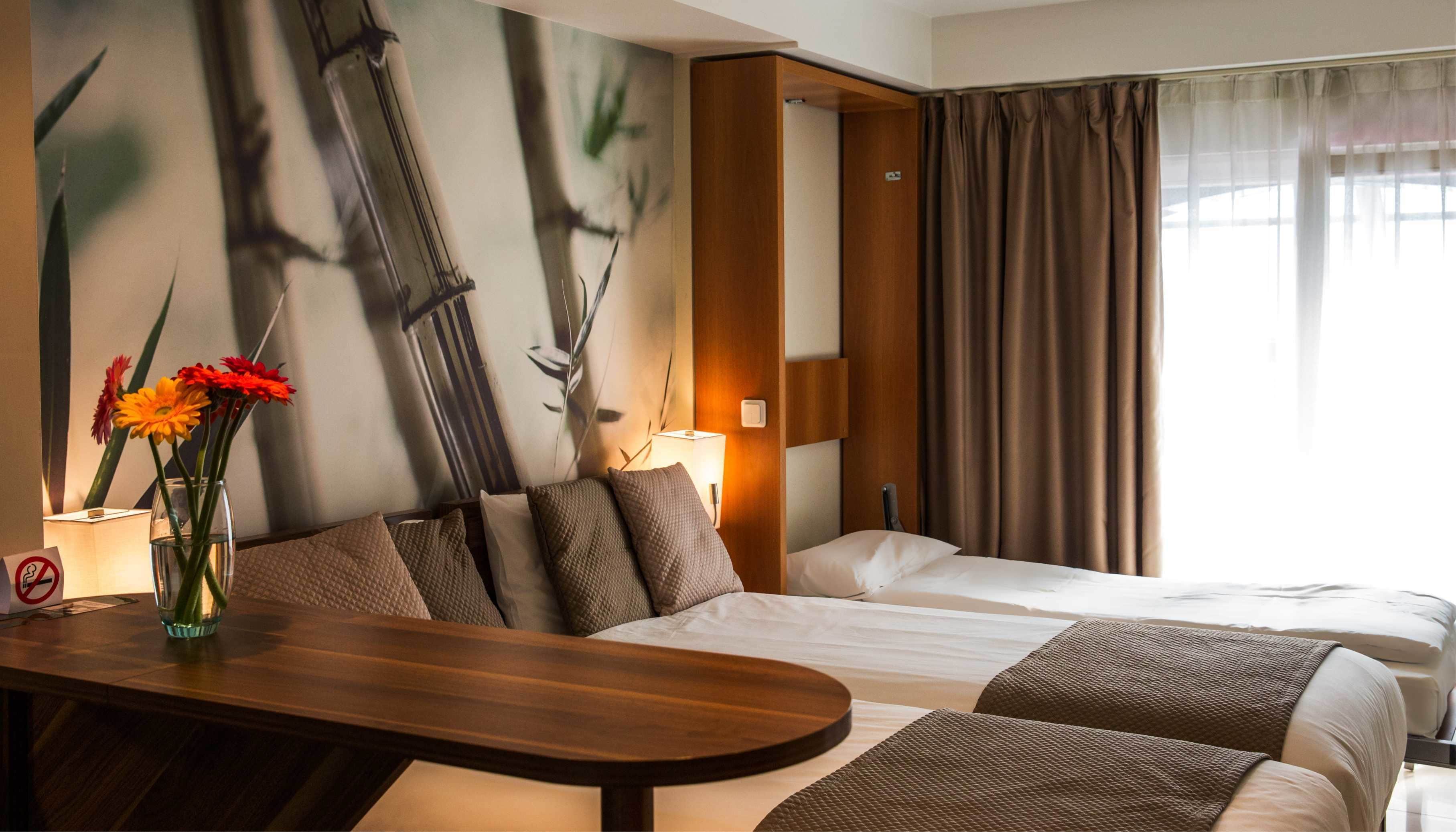 A hotel room with a bed, a desk, and a wall with a painting.