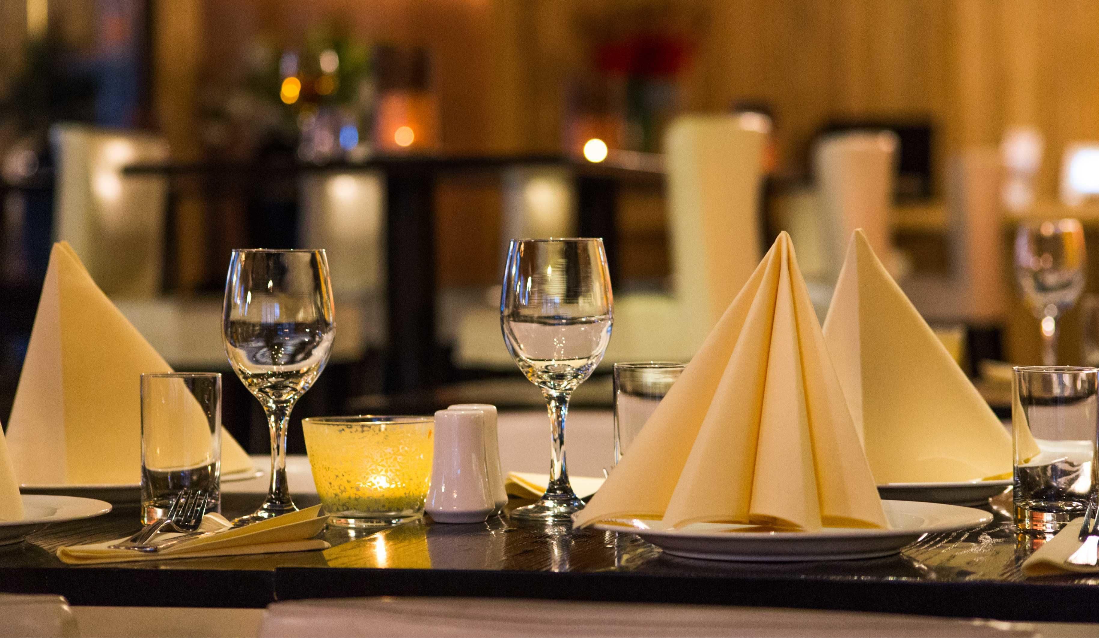 A dining table set with multiple wine glasses, a water glass, and folded napkins.