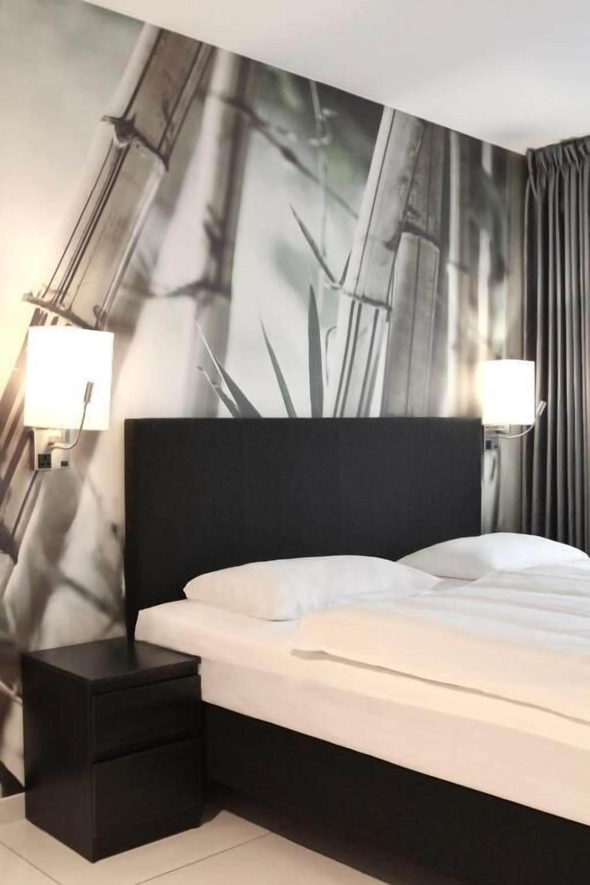 Habitación de hotel con una cama, una mesita de noche y una pared con diseño de bambú.