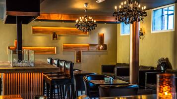 A restaurant interior with a bar area, seating, and a chandelier.