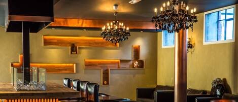 A restaurant interior with a bar area, seating, and a chandelier.