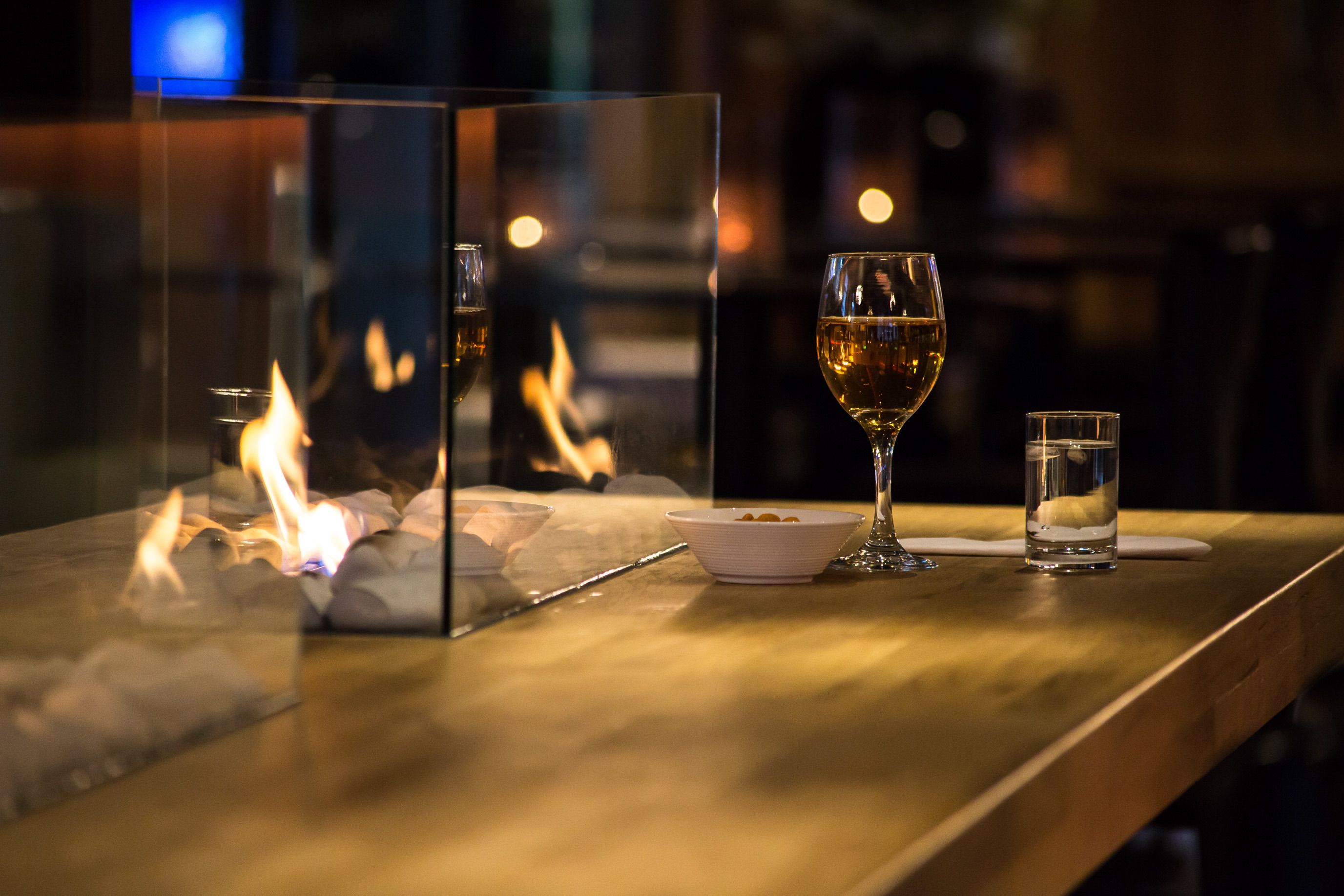 A table with a glass of wine, a small bowl, and a glass of water.