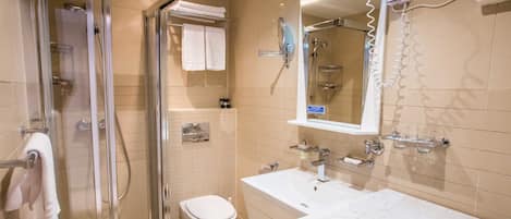 Een moderne badkamer met een glazen douchecabine, een wit toilet, een wastafel met spiegel en een handdoekhouder.