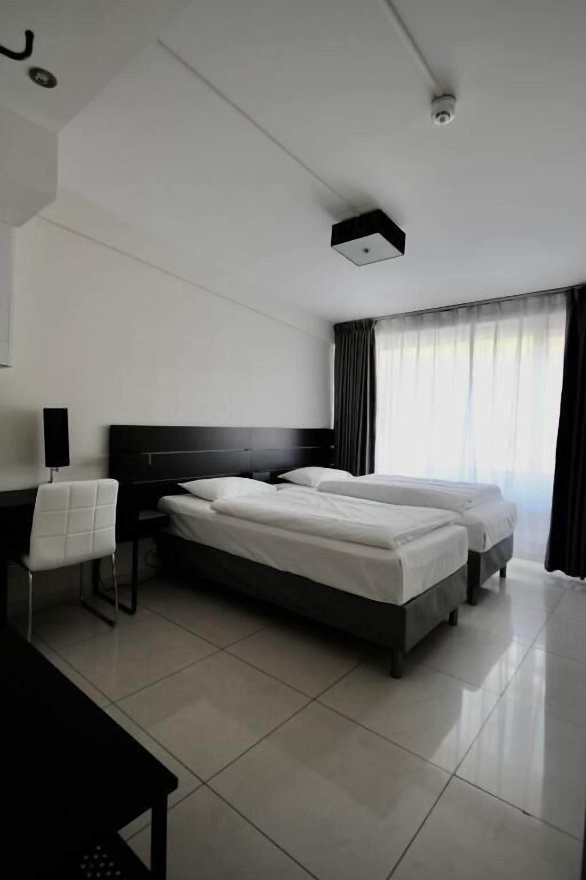 A modern hotel room with a large bed, a desk, and a chair.