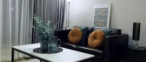 A modern living room with a white coffee table, black sofa, and a black side table.