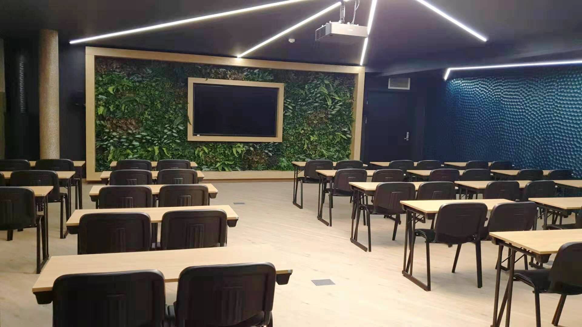 A conference room with a large screen, multiple tables, and chairs arranged for a meeting.