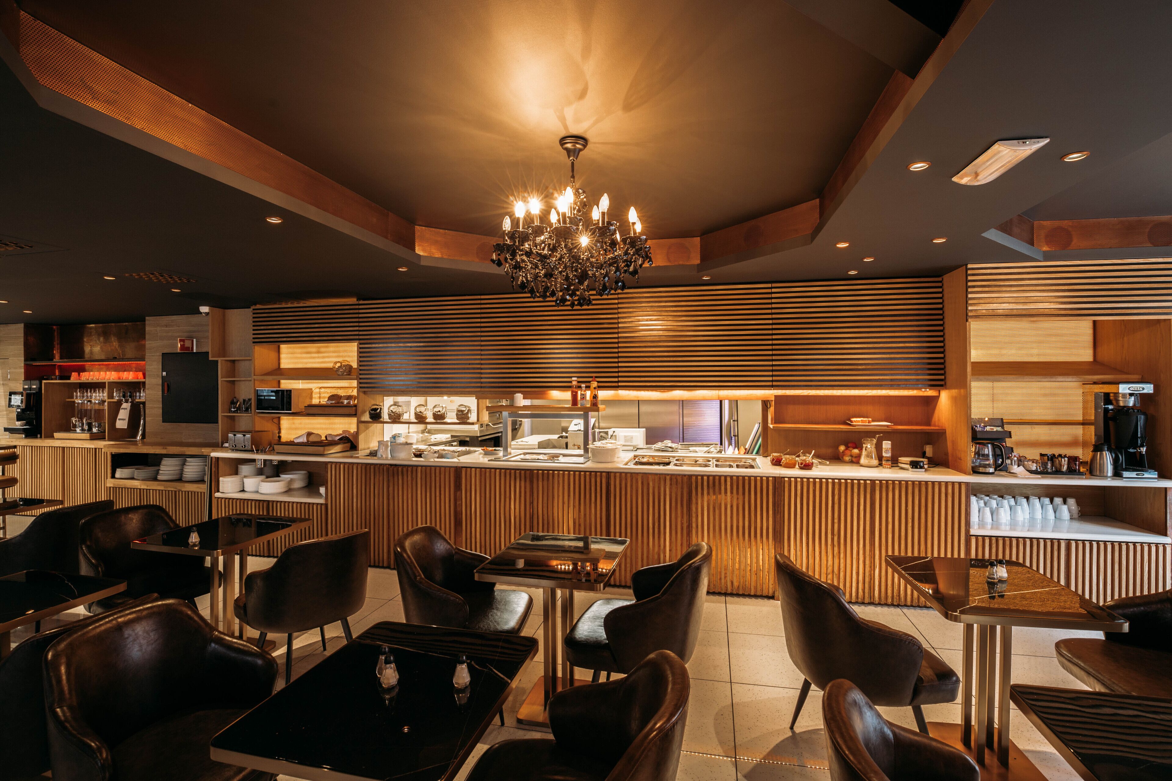 A modern cafe with a central bar, wooden slats on the walls, and leather seating.