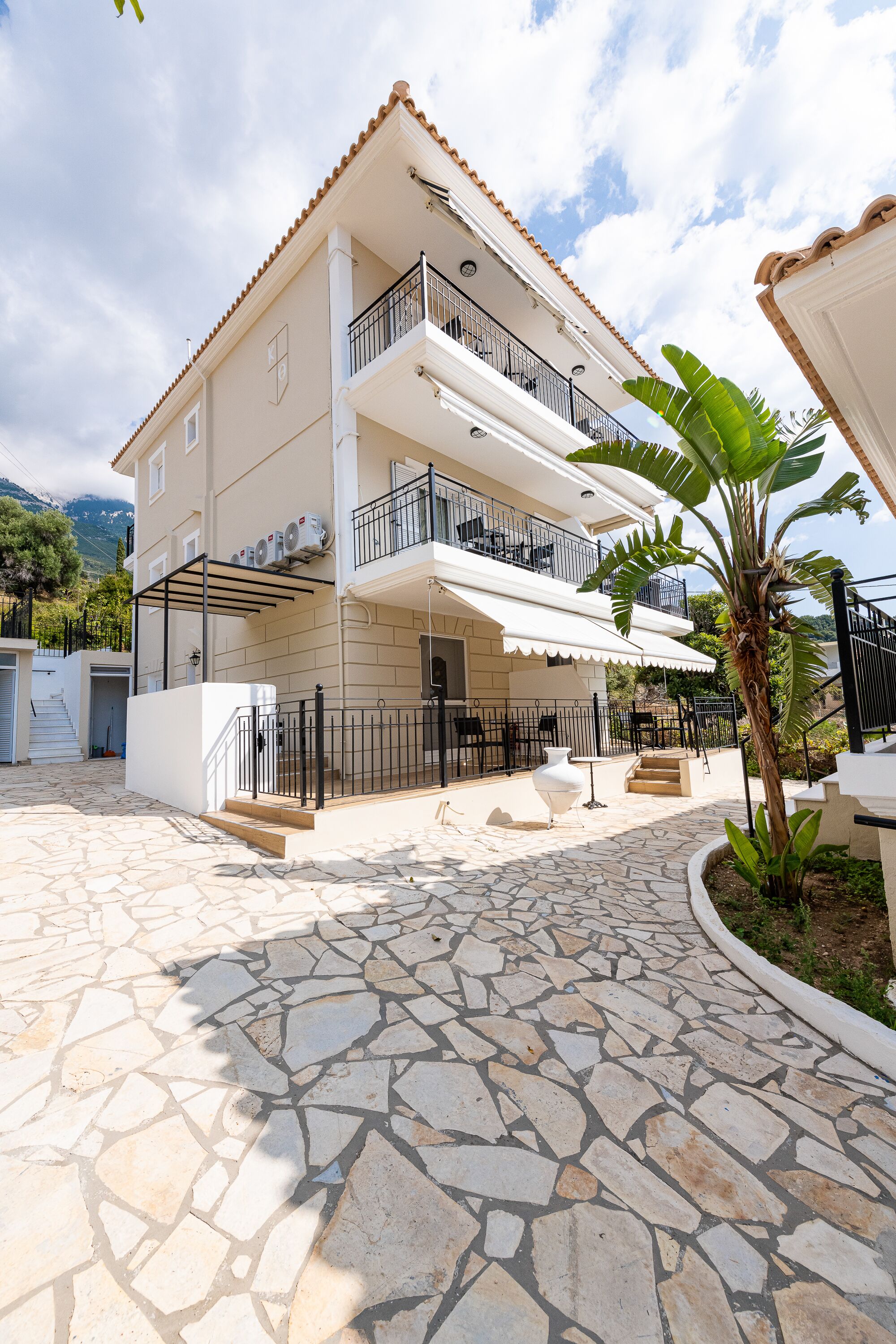 A multi-story building with balconies, a stone-paved courtyard, and a white exterior.