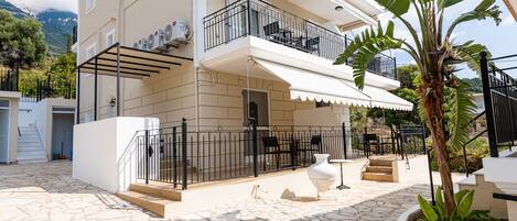 A multi-story building with balconies, a stone-paved courtyard, and a white exterior.
