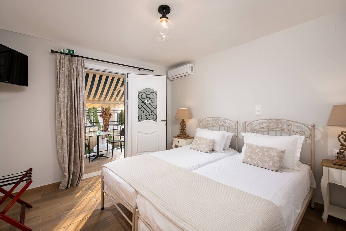 A bedroom with a bed, bedside tables, a lamp, and a view of the outside.