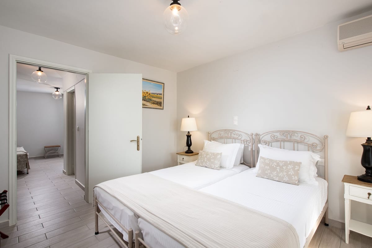 A bedroom with two beds, a nightstand, a lamp, and a painting on the wall.