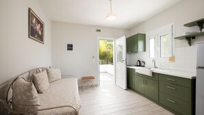 Una habitación moderna con cama, un pequeño banco, una kitchenette y una puerta que da a un balcón.