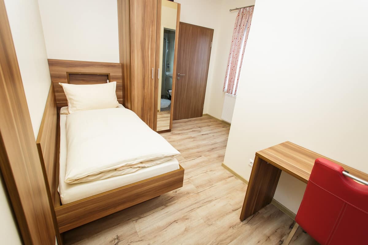 A bedroom with a wooden bed, a desk, and a red chair.