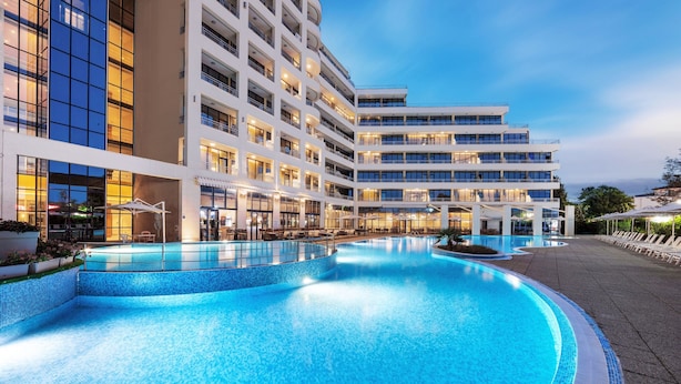 A modern hotel with a large outdoor swimming pool, multiple balconies, and a well-lit facade. - Four Points by Sheraton Sunny Beach (Sunny Beach)