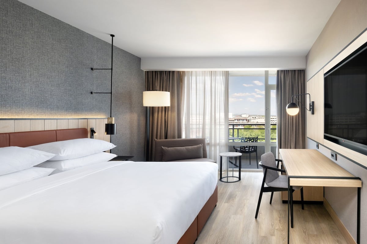 Une chambre d’hôtel moderne dotée d’un grand lit, d’un bureau et offrant une vue sur la ville.