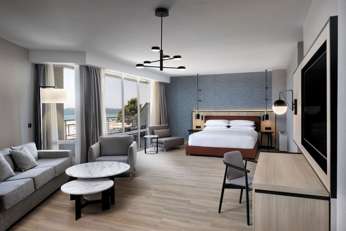Une chambre d’hôtel moderne dotée d’un grand lit, d’un canapé, d’un bureau et offrant une vue sur la ville.