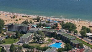 Un resort con diversi edifici, una piscina e una spiaggia con ombrelloni.