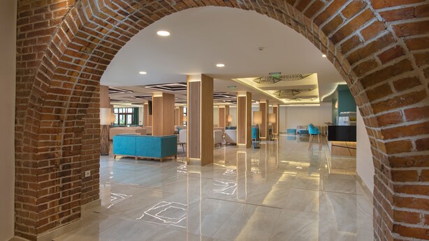 Un'ampia hall con soffitto alto, un arco in mattoni e la reception.