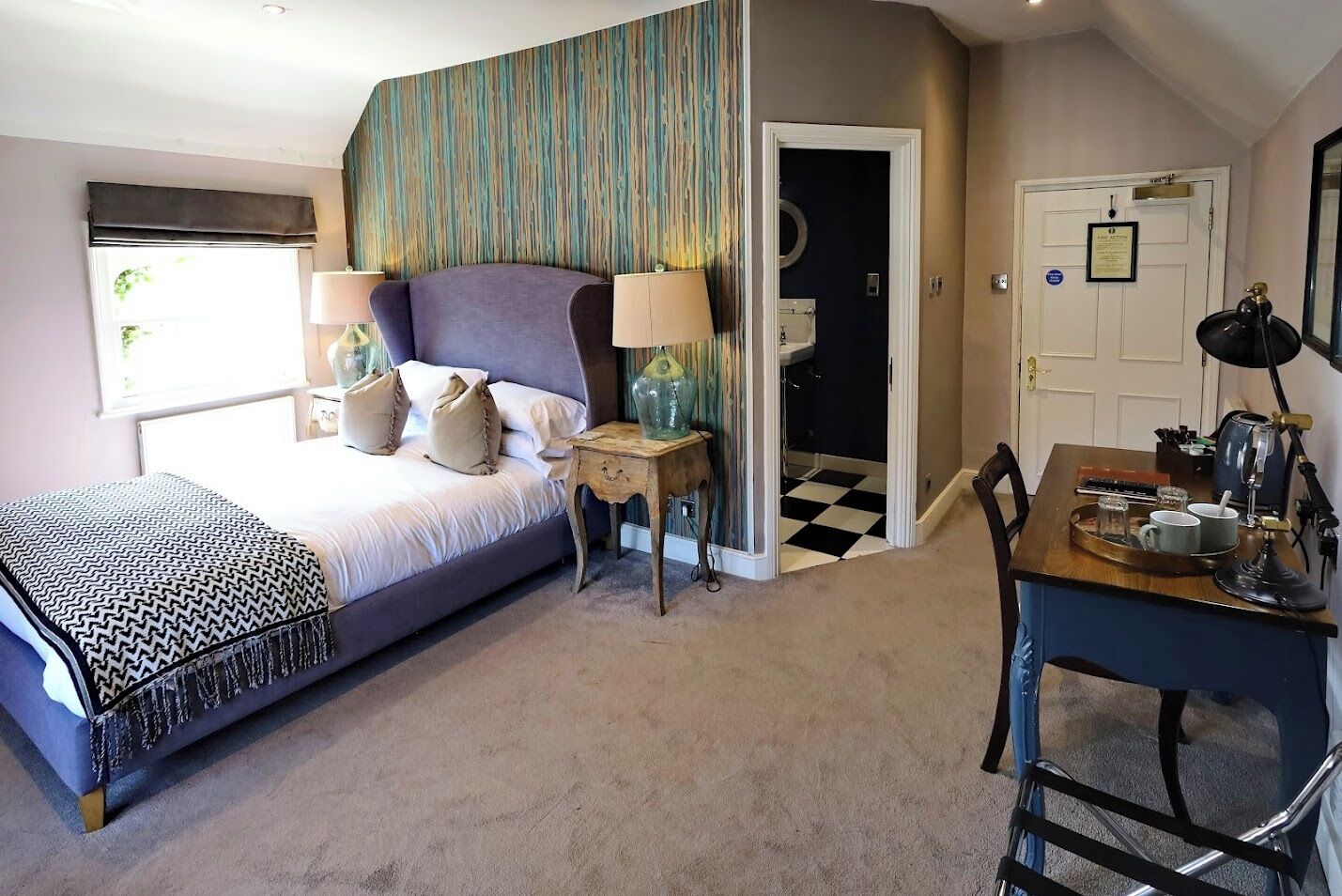 A bedroom with a bed, bedside tables, a desk, and a chair.