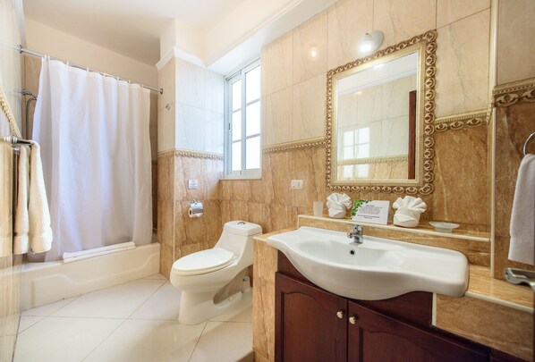 Une salle de bain avec une baignoire, des toilettes, un lavabo et un grand miroir.