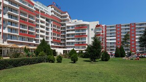 Un hotel de varios pisos con balcones, un patio central y zonas de estar al aire libre.