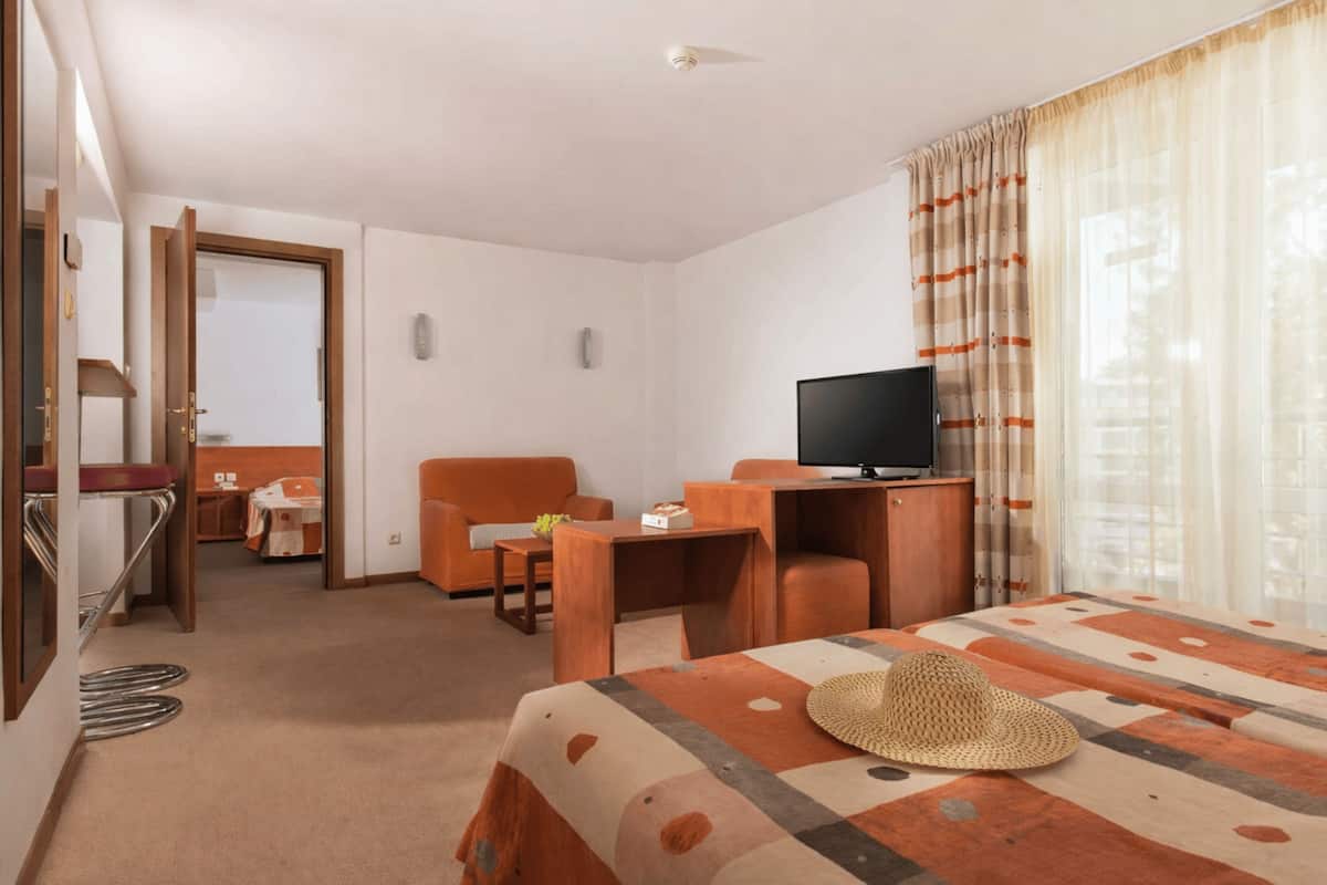 Una habitación de hotel con cama, televisor, escritorio y silla.