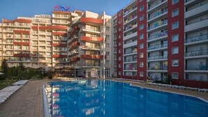 Un hotel con piscina, varios balcones y cielo despejado.