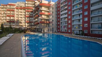 Una piscina al aire libre de temporada, sombrillas, tumbonas