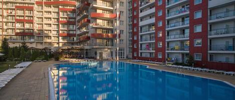 Una piscina al aire libre de temporada, sombrillas, tumbonas
