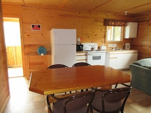 A wooden cabin interior with a kitchen area, a dining table with chairs, and a 'No Smoking' sign. - Timberlane Lodge (Ear Falls)