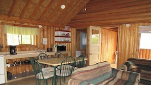 A cozy cabin interior with a dining area, kitchen, and seating space.
