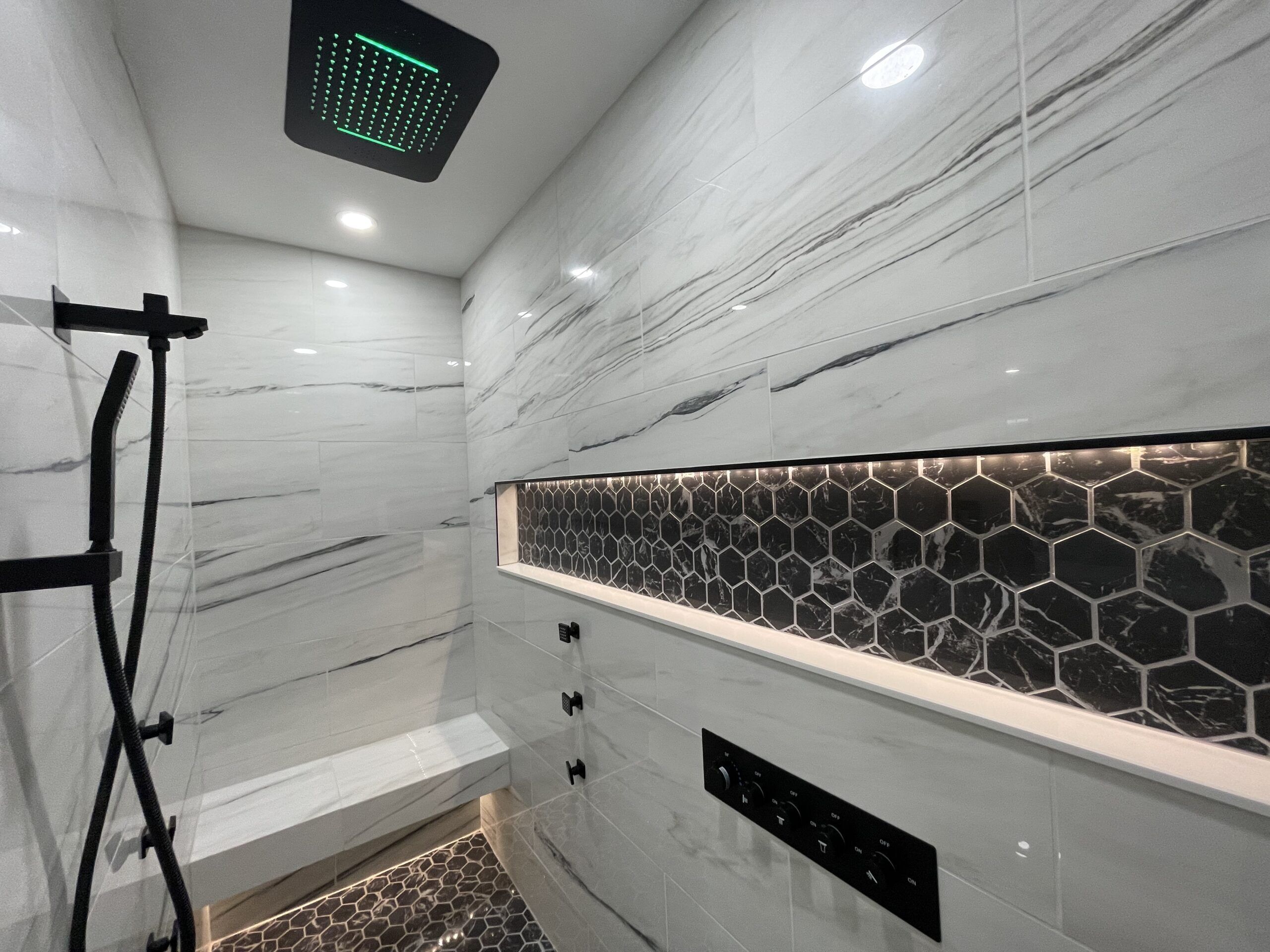 A modern bathroom with a shower, a hexagonal tile backsplash, and a marble wall.