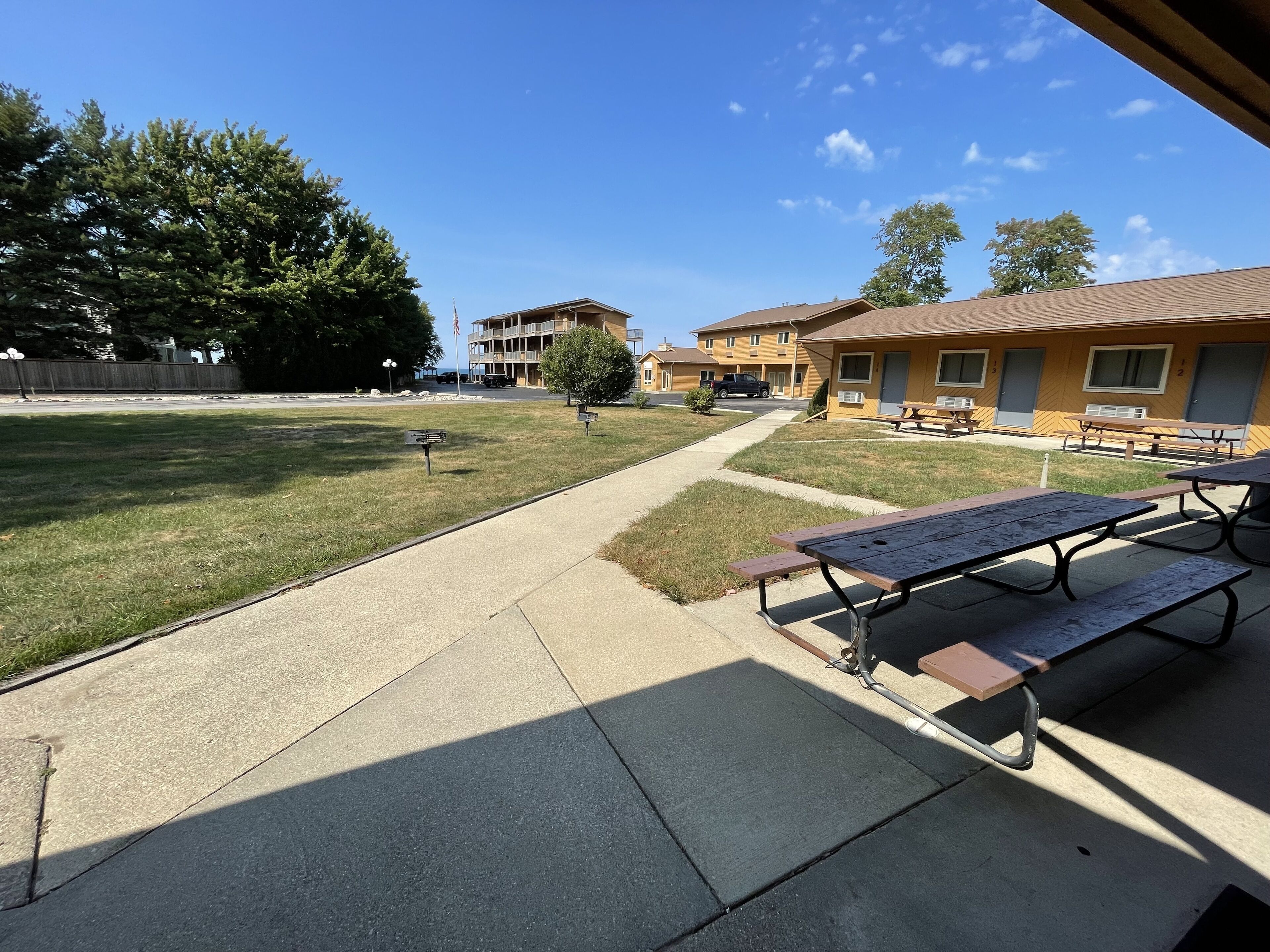 Un patio con mesas de picnic, un sendero y un edificio con varias habitaciones.