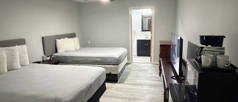 A hotel room with two beds, a ceiling fan, a TV, a microwave, and a coffee maker.