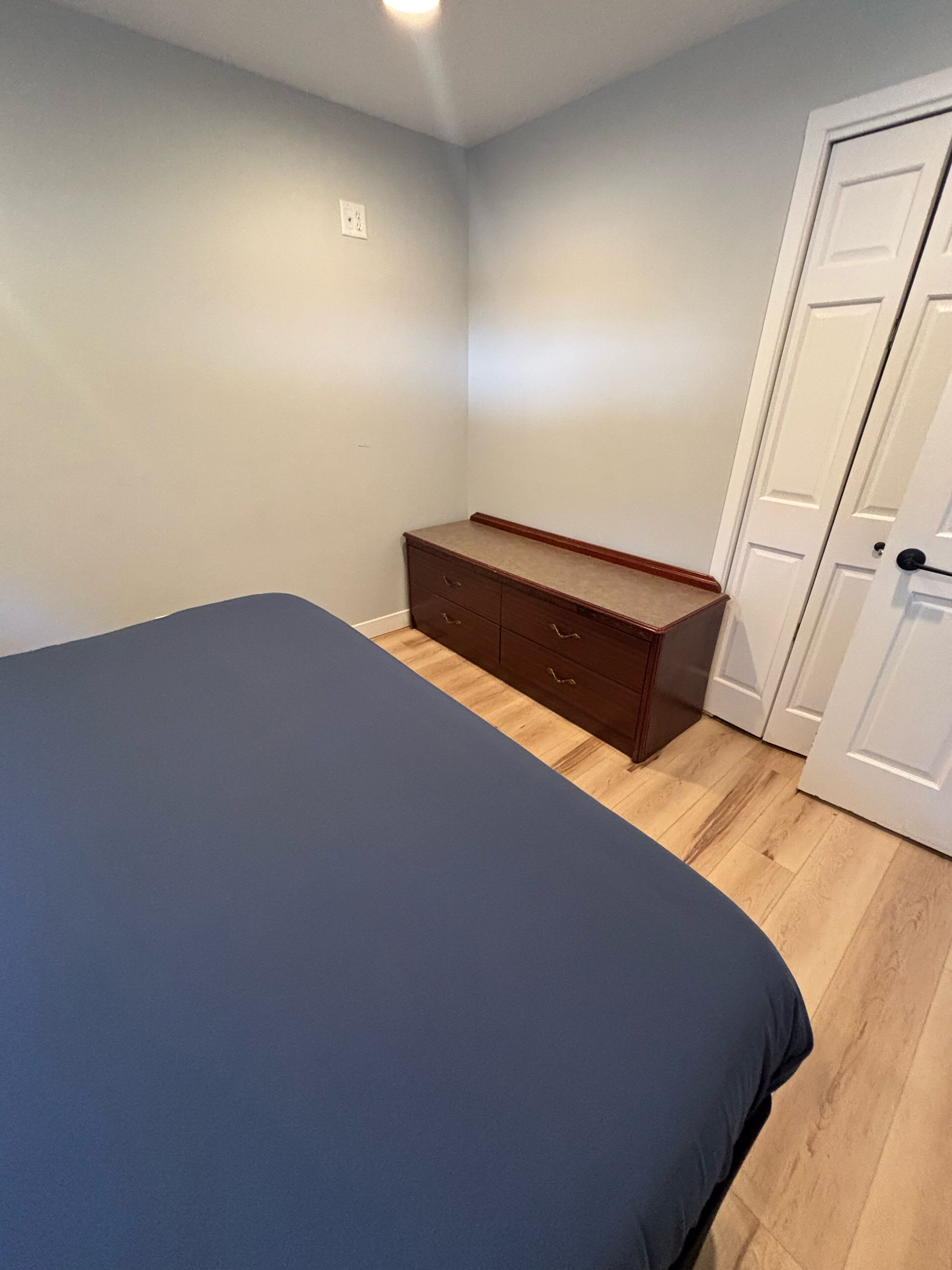 Ein Schlafzimmer mit Bett, Kommode und Tür.